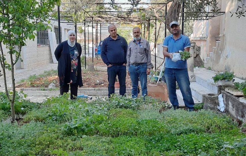 Reema Zghoul standing beside three men in a garden of seedlings